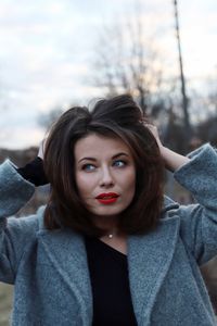 Beautiful young woman with hands in hair looking away during sunset