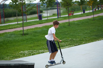 Active ten year old boy riding a scooter in the summer skate park