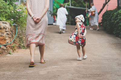 Rear view of mother and daughter walking outdoors