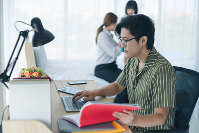 Rear view of man and woman using mobile phone at table