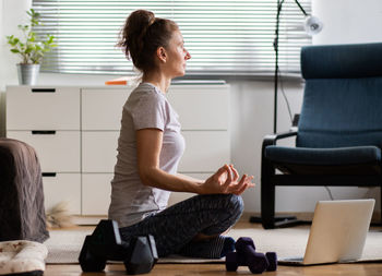 Side view of woman meditating at home