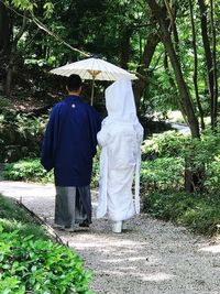 Rear view of people walking on footpath during rainy season