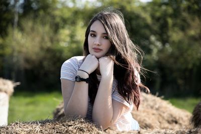 Portrait of teenage girl leaning on hay bale