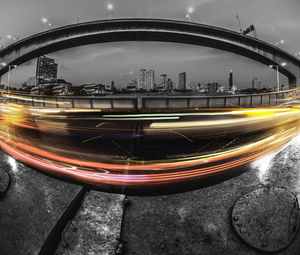 Light trails on bridge in city against sky at night