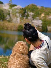 Rear view of woman with dog by lake