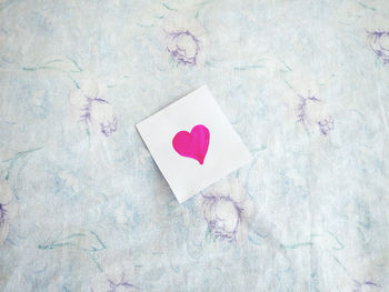 Directly above shot of paper with pink heart shapes on bed