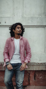 Portrait of young man looking away against wall