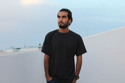 Portrait of young man standing against sky