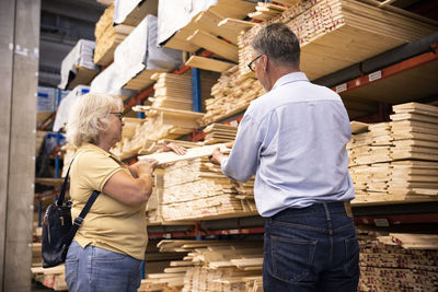 Male and female customers choosing plank at hardware store