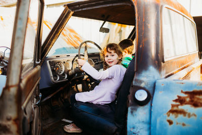 Young brother and sister sitting in vintage truck at sunset