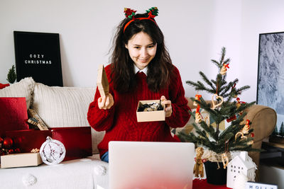 Young woman using digital tablet while sitting on sofa at home