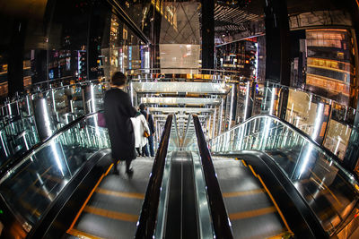 Man walking on escalator in illuminated city