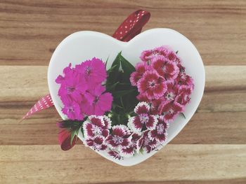 Directly above shot of dianthus in heart shaped container on table