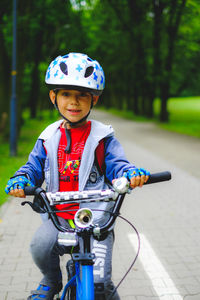 Portrait of smiling boy riding bicycle on footpath at park
