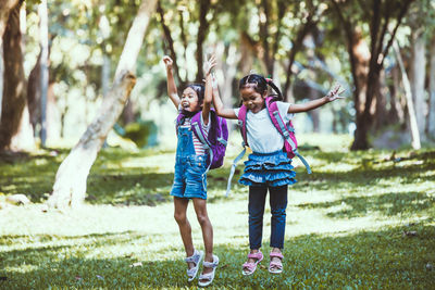 Full length of schoolgirls jumping in park