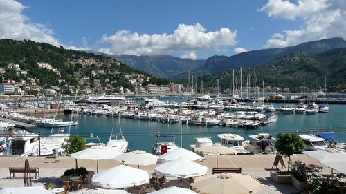 Boats moored in harbor by buildings against sky