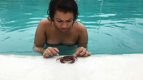 Young woman catching crab while standing in swimming pool