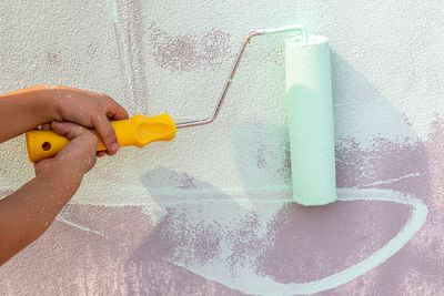 Close-up of person working against yellow wall