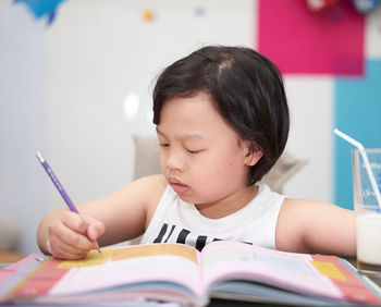 Portrait of boy with book on table