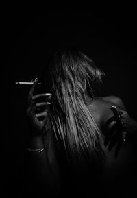 Woman smoking cigarette against black background