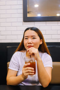 Portrait of young woman drinking drink in restaurant