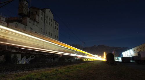 Light trails on road in city against clear sky at night