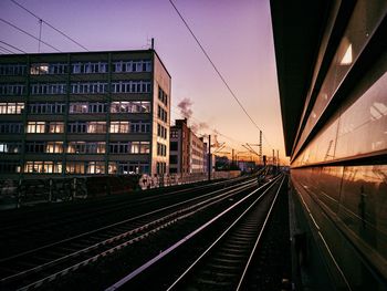 Railroad tracks amidst buildings in city at sunset