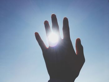 Low angle view of hand against bright sun