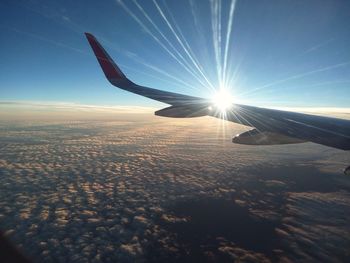 Airplane wing over landscape against blue sky