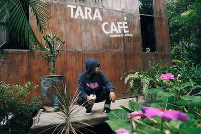 Full length of man sitting by flowers