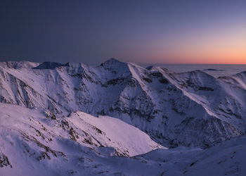 Scenic view of snowcapped mountains against sky during sunset