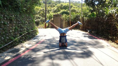 Full length of man performing headstand with legs apart on street