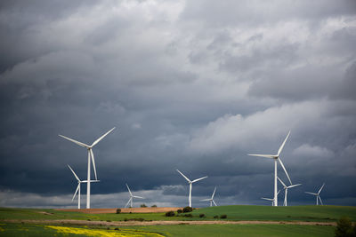 Wide shot of renewable wind power farm windmills in motion with a cloudy epic sky in burgos, spain.
