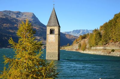 Scenic view of building and mountains against sky, curon venosta