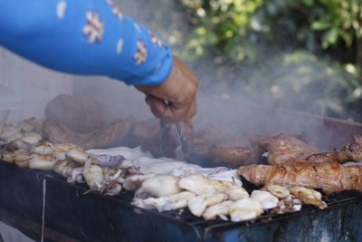 Person preparing food on barbecue grill