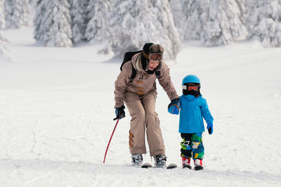 Mature woman and his son skiing on snow covered field