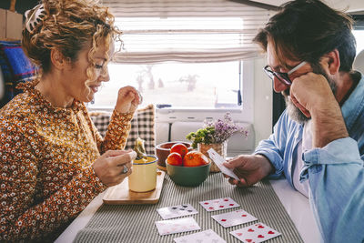 Side view of senior woman giving food at table