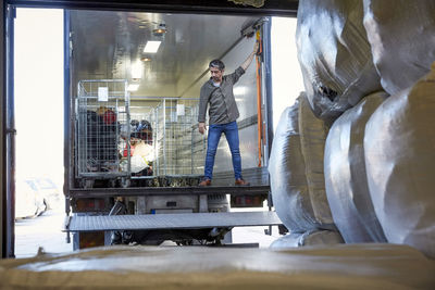 Full length of mature male volunteer standing in semi-truck at warehouse