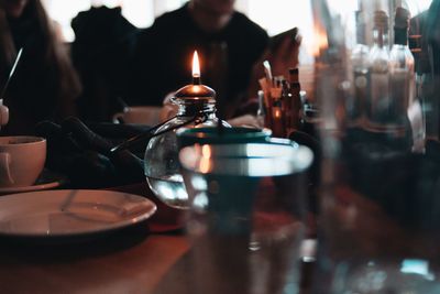 Close-up of lit candle by place setting on table in restaurant
