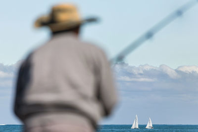 Rear view of man sailing on sea against sky