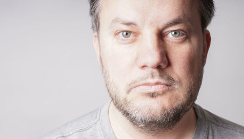 Mid adult man looking at camera - close crop headshot with copy space on gray background