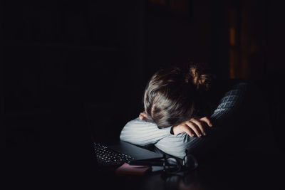 Side view of woman sitting on sofa at home