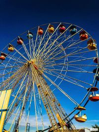 Low angle view of ferris wheel against blue sky