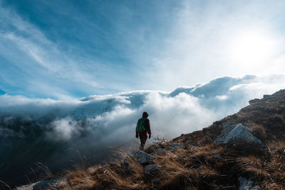 Man standing on mountain against cloudy sky