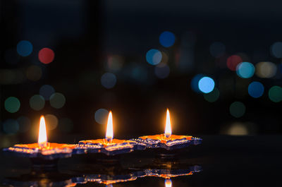 Clay diya lamps lit on dark background with colorful bokeh lights. diwali festival concept.