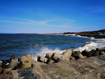 Scenic view of stone walkway with sea against blue sky