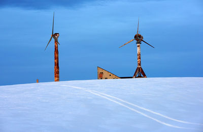 Windmills on snow covered landscape against sky at dusk