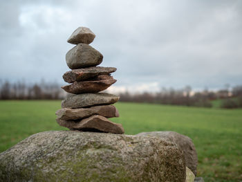 Stack of stones on field against sky