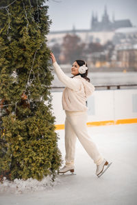 Full length of young woman standing against trees