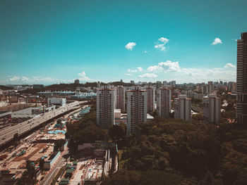 High angle view of buildings in city against blue sky
